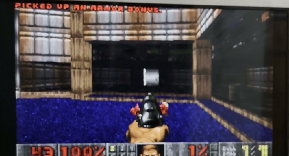 A frame of Doom running on the TV: a brown and blue room, the status bar showing 43 ammo and 100% health.
